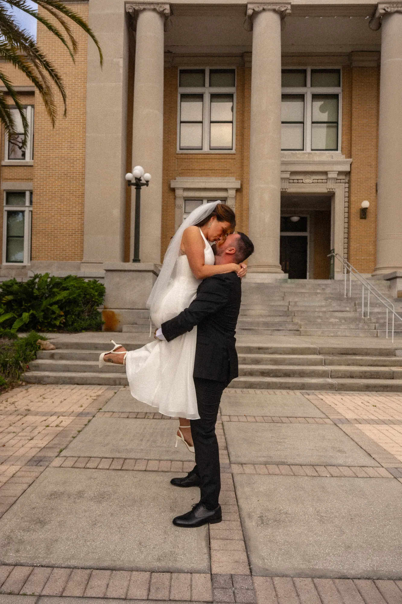 Groom lifting the bride into a kiss on the courthouse steps