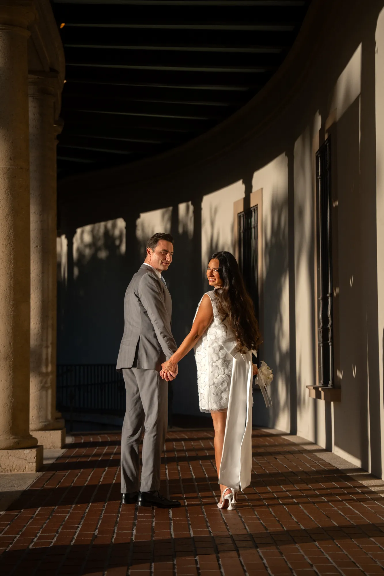 Couple strolling a shaded colonnade during their destination elopement