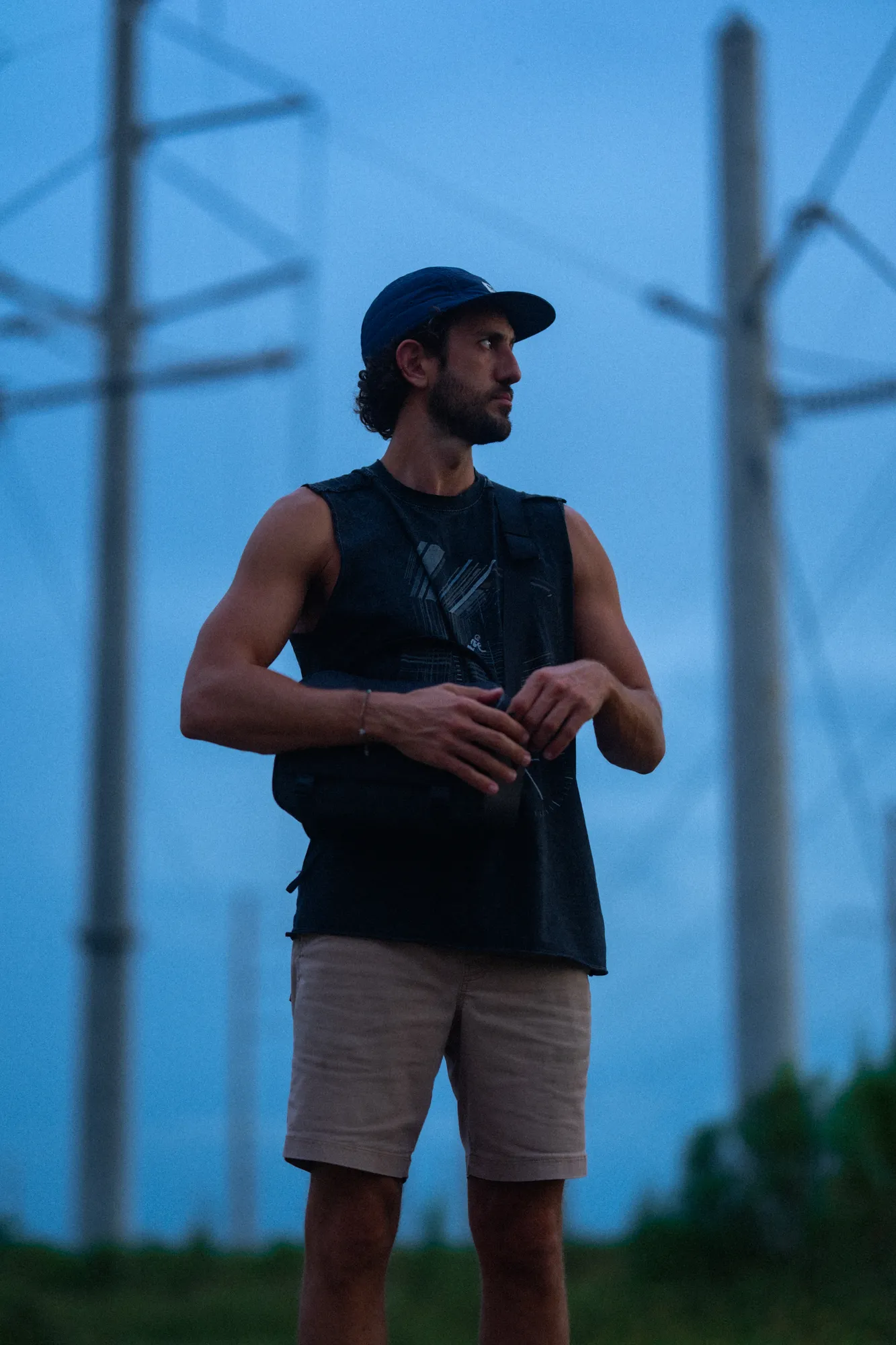 Blue-hour portrait of a man beneath power lines at dusk