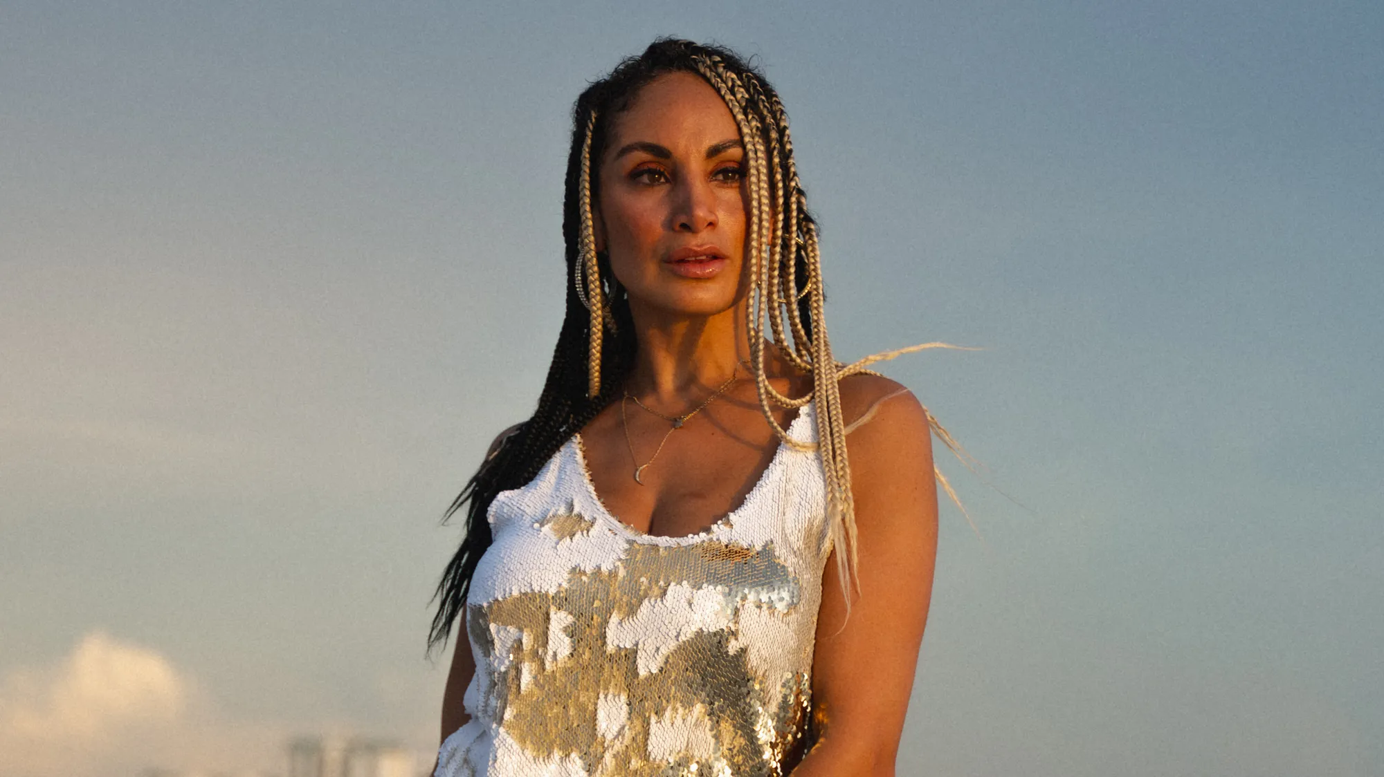 Golden-hour beach portrait in a sequin dress with braids catching the light