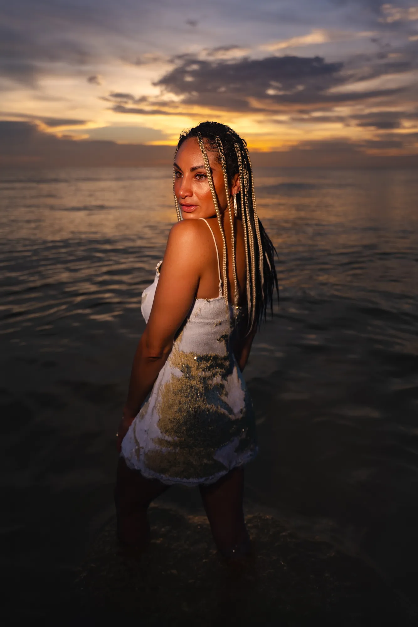 Editorial portrait standing in the Gulf at sunset with braided hair and a sequin dress