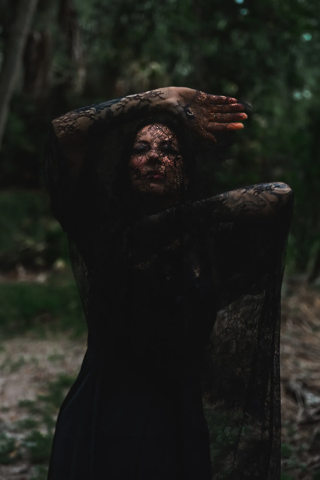 Moody fine-art portrait veiled in black lace under the oaks